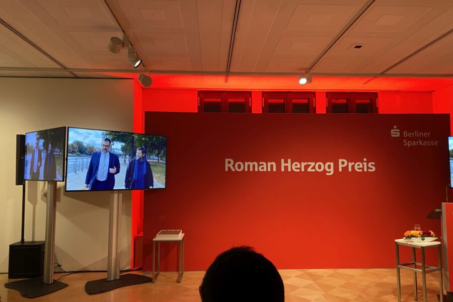 Fotowand mit Schriftzug "Roman Herzog Preis" und Bildschirm mit Still aus dem Videoporträt von meet2respect.